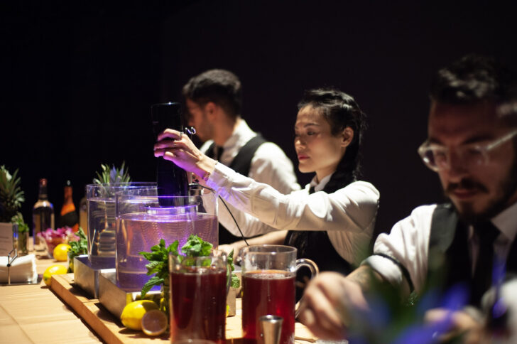 Mixologists behind a bar making cocktails