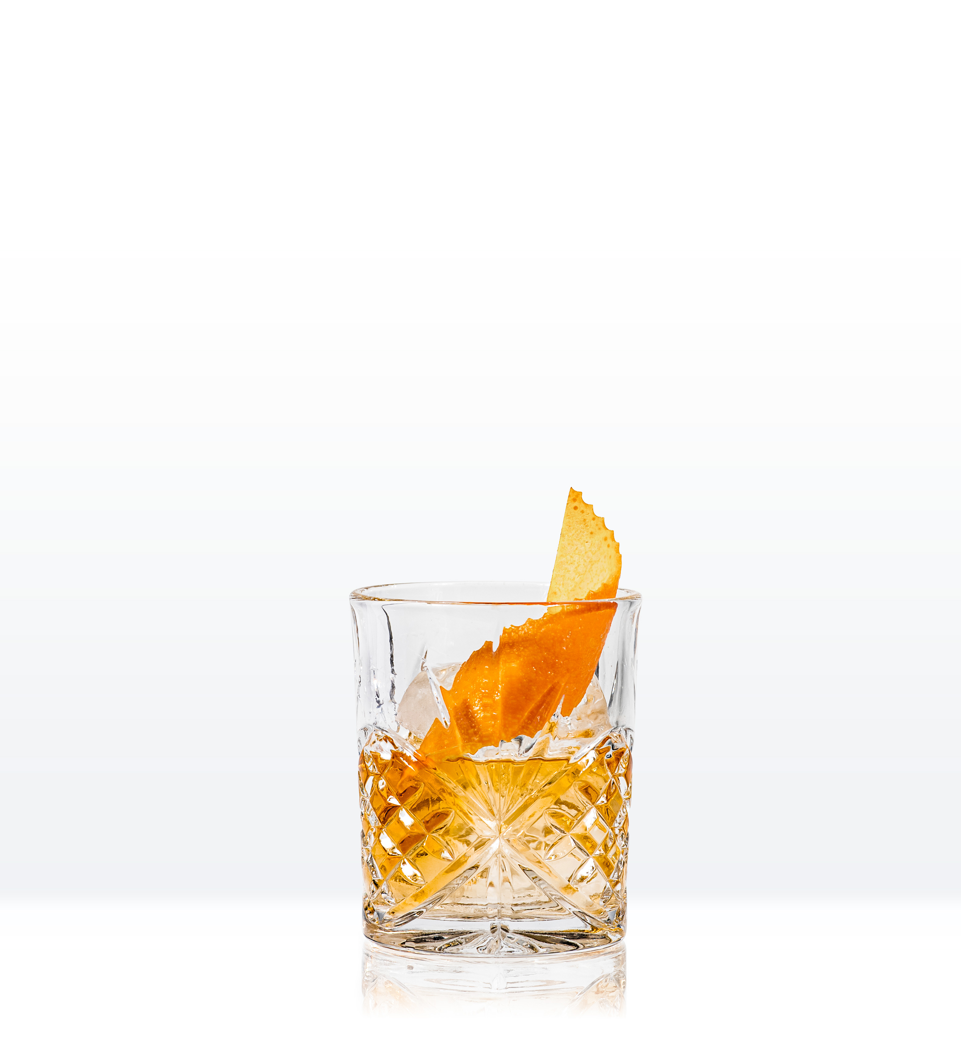 Whiskey cocktail in crystal lowball glass garnished with orange twist