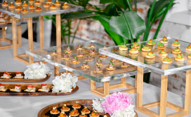 Food station with acrylic platters on wooden elevations displaying multiple hors d'oeuvres