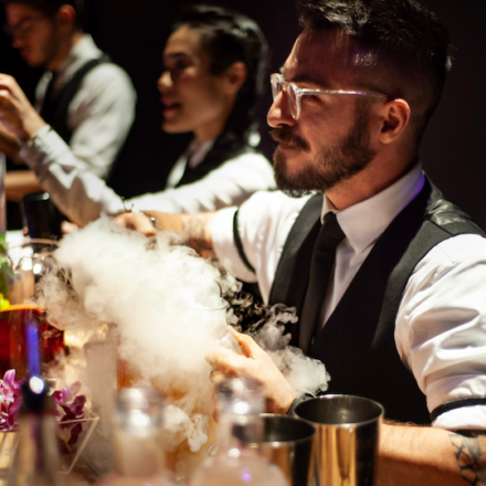 Mixologists making cocktail with dry ice and smoke