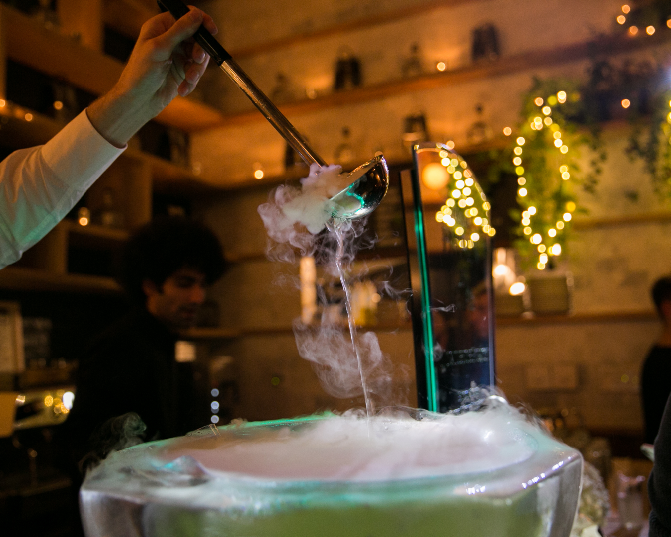 Mixologist pouring alcoholic punch with dry ice