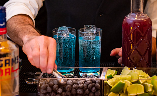 Professional mixologist preparing a blue, custom cocktails